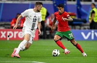 Spieler von Portugal und Slowenien im Zweikampf während eines Fußballspiels.