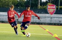 Zwei junge Arsenal-Spieler trainieren auf einem Kunstrasenplatz mit Ball und Hütchen.