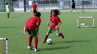 Kinder spielen Fußball auf einem Trainingsplatz mit kleinen Toren.