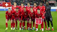 Schweizer Fußballnationalmannschaft posiert vor einem Spiel in roten Trikots.