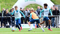 Kinder spielen Fußball auf dem TSG AOK Campus, Zuschauer beobachten das Training am Spielfeldrand.