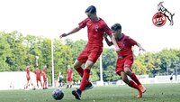 Zwei Jugendfußballer des 1. FC Köln kämpfen um den Ball auf einem Spielfeld.
