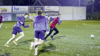 Fußballspieler sprinten während eines Trainings auf einem Kunstrasenplatz.
