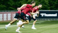 Fußballspieler sprinten während eines Trainings auf einem Sportplatz.