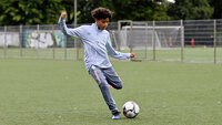 Jugendlicher Fußballspieler beim Passspiel auf einem Trainingsplatz.
