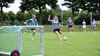 Frauenfußballerinnen trainieren Torschuss auf dem Rasenplatz mit kleinen Toren