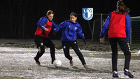 Fußballspielerinnen des 1. FC Magdeburg im Zweikampf beim Wintertraining vor dem Tor auf verschneitem Platz