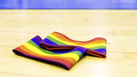 Regenbogen-Kapitänsbinde liegt in der Sporthalle auf dem Hallenboden, Symbol für Vielfalt und Respekt
