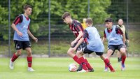 Spieler von Bayer Leverkusen trainieren in einem intensiven Zweikampf auf dem Fußballplatz.