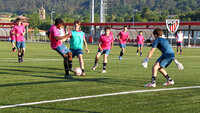 Jugendliche beim Fußballtraining auf dem Platz von Athletic Bilbao mit Torwart im Vordergrund.