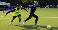 Zweikampf zwischen zwei Fußballspielern während eines Trainings auf einem beleuchteten Kunstrasenplatz.