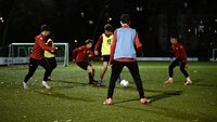 Jugendfußballer trainieren am Abend auf dem Kunstrasenplatz mit Leibchen und Ball