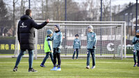 Trainer gibt Anweisungen an Kinder beim Fußballtraining auf einem Sportplatz.