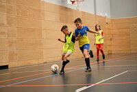 Nachwuchsspieler kämpfen mit Körpereinsatz um den Ball in einer Sporthalle.