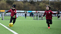 G-Junioren-Torspieler mit Ball am Fuß beim Training auf dem Kunstrasen. Ein Mitspieler läuft neben ihm.