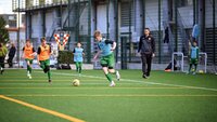 Jugendfußballspieler im grünen Trikot dribbelt den Ball während eines Trainingsspiels.