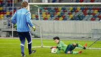 Gezieltes Torwarttraining für Kinder: Ein junger Keeper hechtet und sichert den Ball unter Aufsicht seines Trainers.