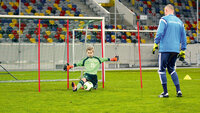 Junger DFB-Torwart blockt einen Ball im 1-gegen-1-Training unter Aufsicht seines Torwarttrainers im Stadion.