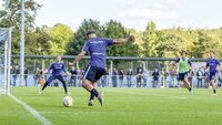 Ein Fußballspieler in violettem Trikot schießt auf das Tor während eines Trainingsspiels.