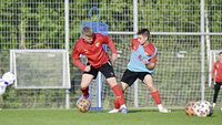 Jugendspieler trainieren Zweikampf und Ballkontrolle beim Fußballtraining auf dem Rasenplatz.