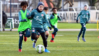 Mehrere Kinder in türkisfarbenen Trainingssets spielen ein kleines Feldspiel, ein Spieler dribbelt zentral nach vorne.