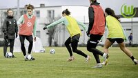 Fußballspielerinnen des VfL Wolfsburg trainieren mit Ball und Hütchen auf dem Platz.
