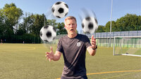 Trainer jongliert auf dem Fußballplatz mit drei Bällen bei sonnigem Wetter.