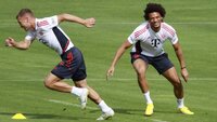 Zwei Fußballspieler des FC Bayern München trainieren auf dem Spielfeld.