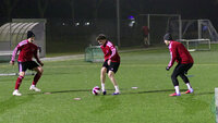Abendtraining auf Kunstrasen: Drei Spieler im Dreieck, Ballannahme und kurzer Pass in einer Technikübung mit Minitoren.