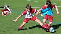 Jugendspieler des 1. FC Köln kämpfen um den Ball auf dem Trainingsplatz.