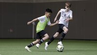 Zwei junge Fußballspieler im Zweikampf während eines Trainings in einer Halle.