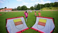Kinder spielen Fußball auf dem Rasenplatz des SC Münster 08, Mini-Tore im Vordergrund.