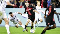 Florian Wirtz von Bayer 04 Leverkusen dribbelt im Bundesligaspiel an Freiburgs Nicolas Höfler vorbei, der zum Tackle ansetzt.