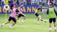 Spieler der deutschen Nationalmannschaft trainieren intensiv vor Zuschauern auf dem Fußballplatz.