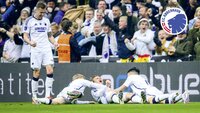 Drei Spieler des FC Kopenhagen feiern gemeinsam auf dem Spielfeld liegend.