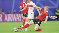 Ein österreichischer Fußballspieler im roten Trikot grätscht nach dem Ball während eines Spiels.