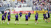 Fußballnationalmannschaft beim Aufwärmen im Stadion vor gefüllten Zuschauerrängen bei einem großen Turnier.
