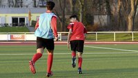 Fußballspieler trainieren auf einem Kunstrasenplatz bei Sonnenuntergang.
