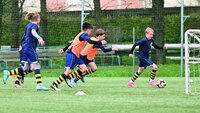 Kinder spielen Fußball auf einem Trainingsplatz und nähern sich dem Tor.