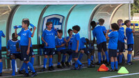 Eine Jugendfußballmannschaft des KRC Genk macht eine Trinkpause und erfrischt sich an der Ersatzbank mit Wasser.
